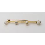 A FOUR PEARL BAR BROOCH mounted in yellow metal, the four pearls are different shapes and sizes from