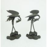 A PAIR OF CHINESE BRONZE JOSS STICK HOLDERS each cast as storks with lily pads and standing on waves