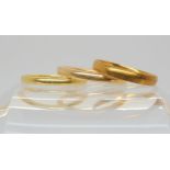 Three 18ct gold wedding rings, one with Glasgow 1887 hallmarks, size O1/2, thicker of the two with