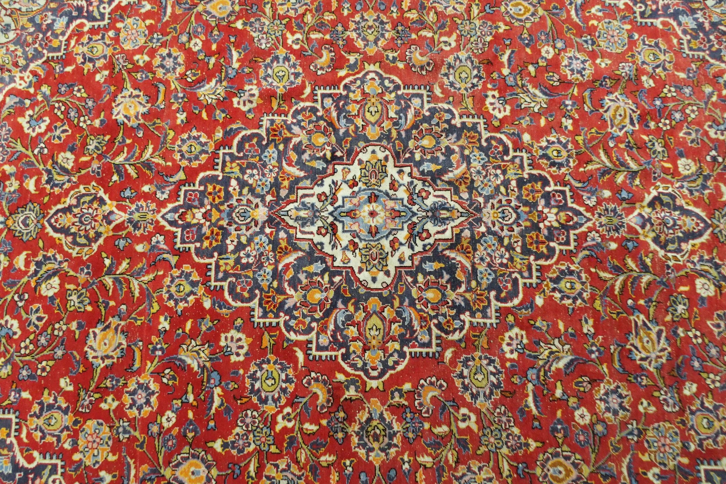 A red ground Kashan wool rug with a blue and cream central medallion, matching spandrels and a - Image 2 of 5