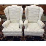 A pair of 20th century wing back armchairs with white patterned upholstery on cabriole supports (