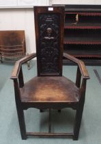 A Victorian baronial style hall armchair with carved back panel on stretchered supports, 121cm