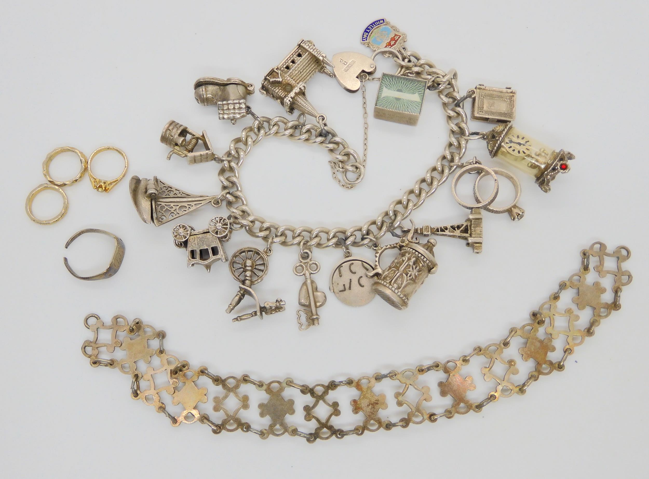 A silver charm bracelet with fifteen attached silver and white metal charms, and a silver bracelet