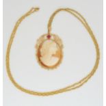 A yellow metal mounted cameo pendant set with a red gem, 4.6cm x 3cm, with a yellow metal rope