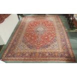 A red ground Kashan wool rug with a blue and cream central medallion, matching spandrels and a