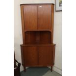 A mid 20th century teak corner cabinet with pair of cabinet doors over open shelf over pair of