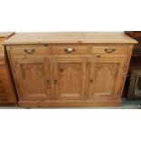 A 20th century pine sideboard with three drawers over three gothic style carved panel cabinet doors,