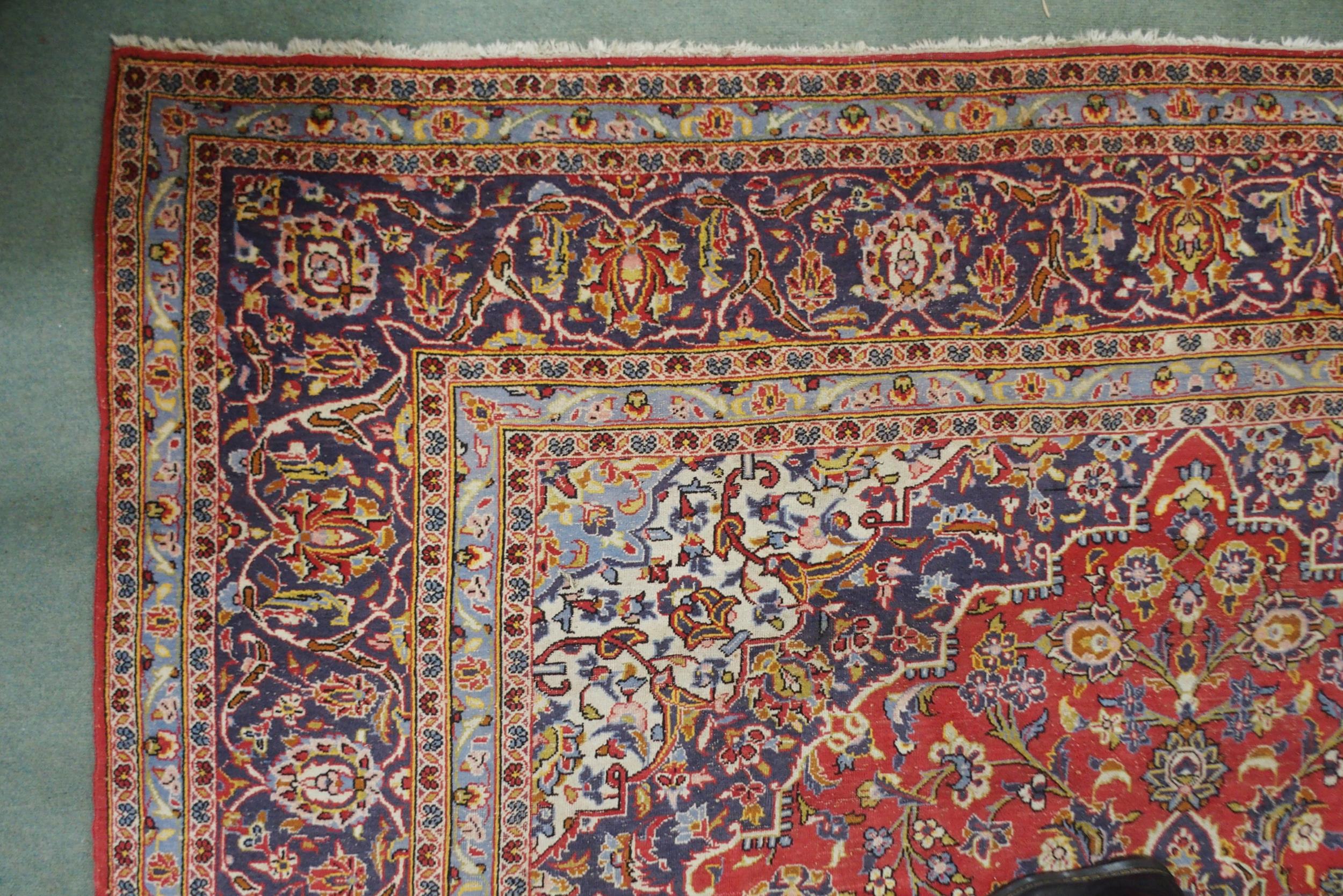 A red ground Kashan wool rug with a blue and cream central medallion, matching spandrels and a - Image 3 of 5