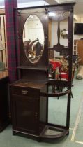 A late Victorian stained oak mirror backed hall stand with oval bevelled glass mirror over single