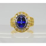 A bright yellow metal ring set with a synthetic sapphire and clear gems, the shank stamped 750,