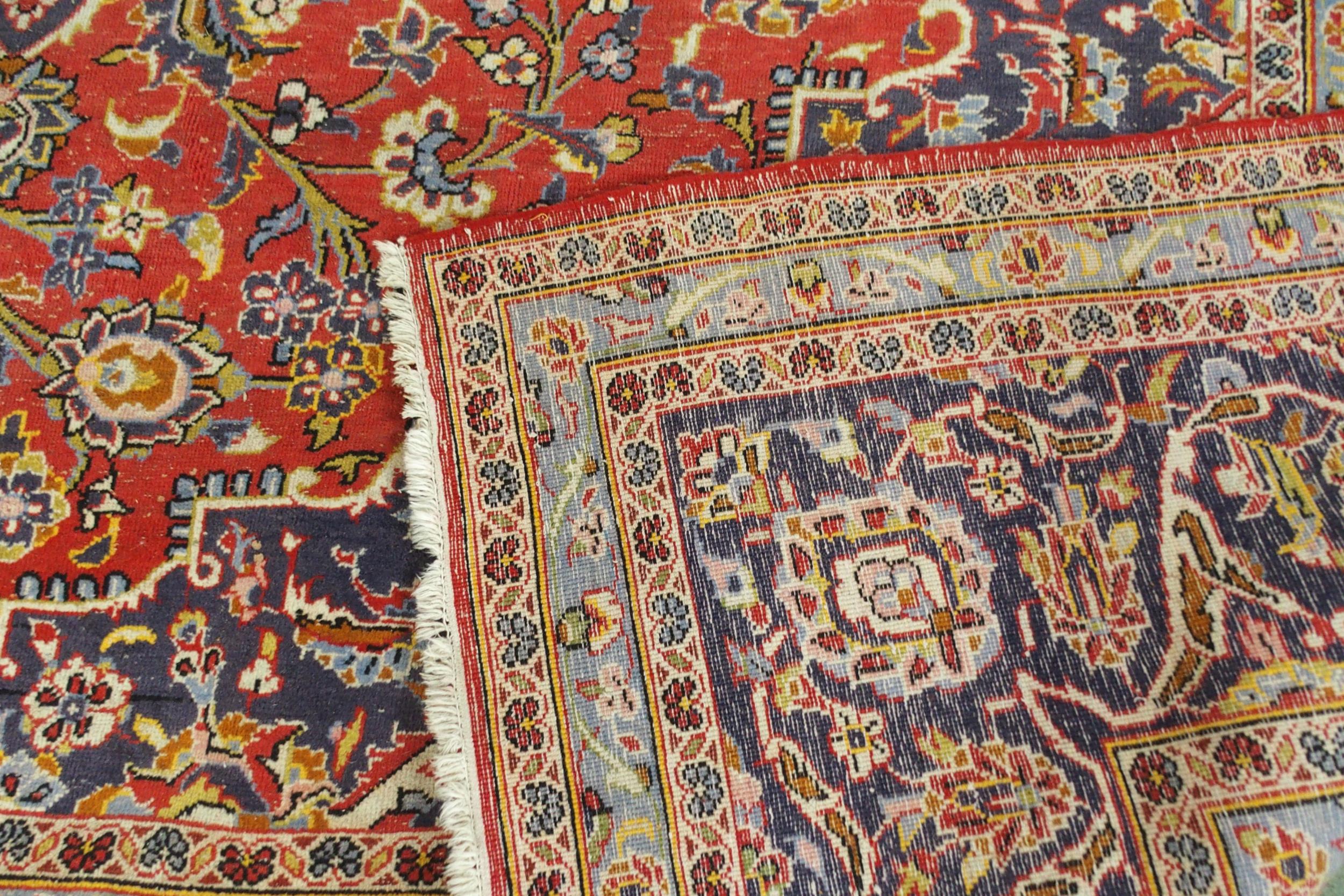 A red ground Kashan wool rug with a blue and cream central medallion, matching spandrels and a - Image 4 of 5