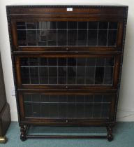 A 20th century oak three tier leaded glass fall front bookcase on stretchered barley twist supports,
