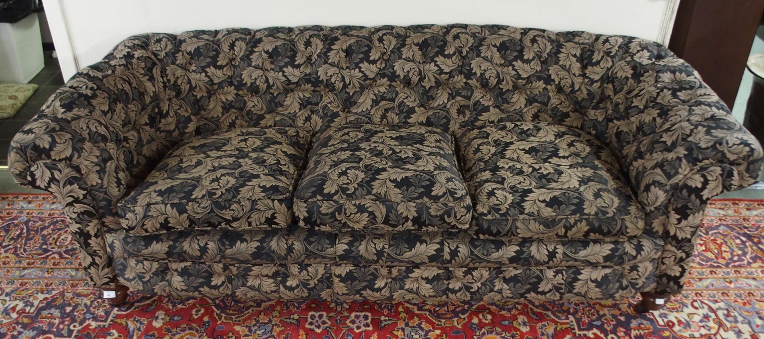 A Victorian button back three seater settee upholstered in a black and gilt acanthus leaves fabric