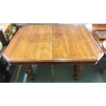 A Victorian oak extending wind out dining table with three additional leaves on turned supports