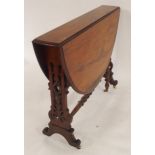 A Victorian rosewood topped drop leaf table with carved fretwork supports terminating in ceramic