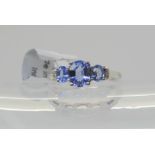 A 9ct white gold three stone tanzanite and diamond accent  ring, finger size K, weight 2.5gms