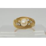 A bright yellow metal ring with a woven texture set with diamonds and a pearl, set with estimated