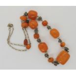 A necklace of amber coloured beads with a white metal decorative chain, weight 21.5gms Condition