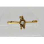 A 15ct gold brooch of a bear holding a pearl, length 3.2cm x 1.4cm, weight 3.8gms Condition Report:
