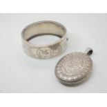 A silver bangle engraved with a bird, and a white metal Victorian heavily engraved locket