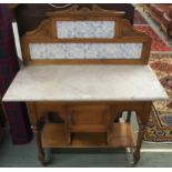A Victorian oak washstand with blue and white tiled splashback over marble top over single door on