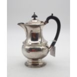 A George VI silver hot water pot, of baluster form, on a stepped circular base, with an ebonised