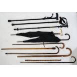 Various walking sticks and umbrellas, two sticks having silver mounts, another with screw-off handle