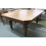 A Victorian oak extending dining table and three leaves with shaped top on turned supports
