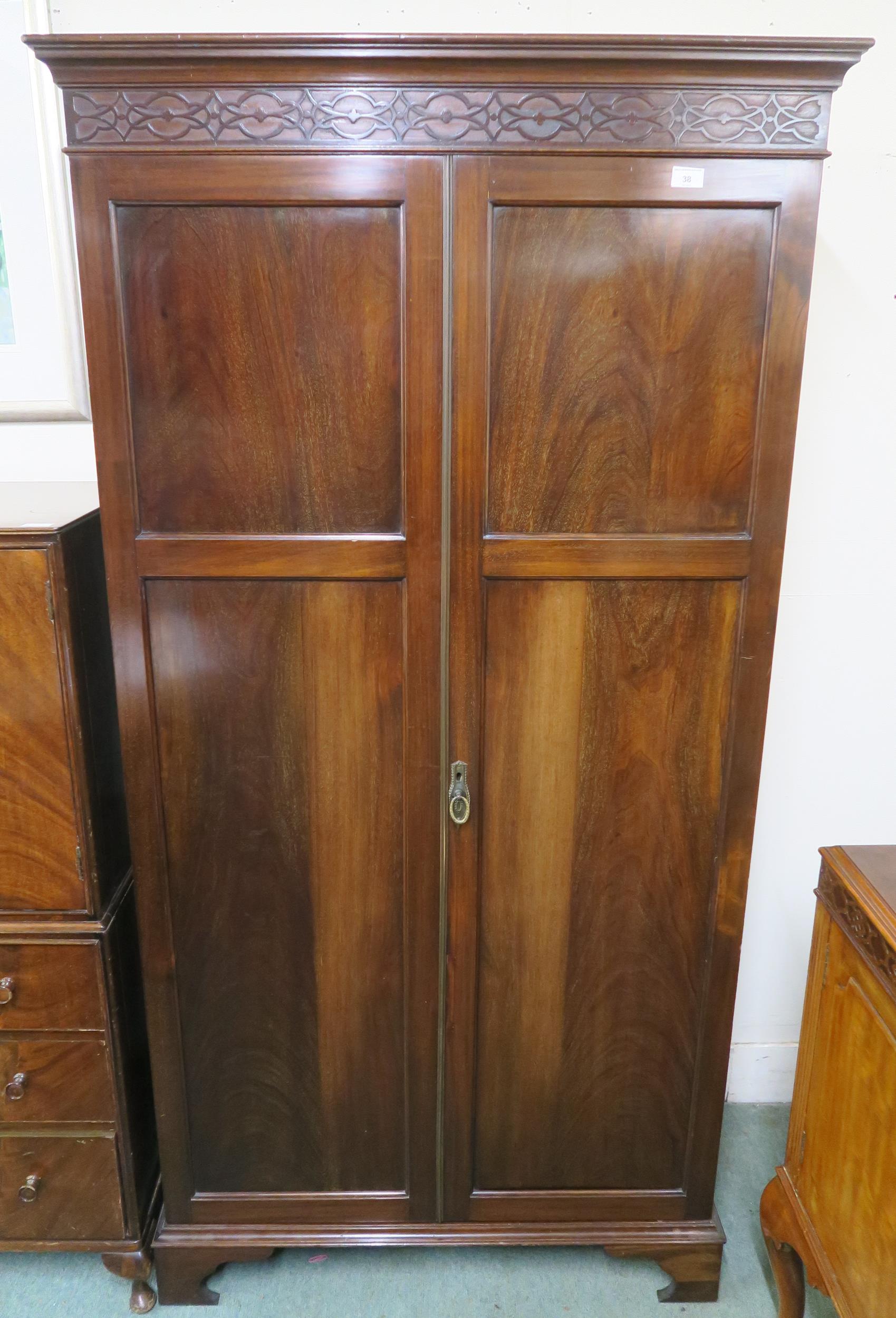 A 20th century mahogany wardrobe with moulded cornice over pair of panel doors on bracket base,