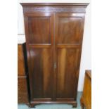 A 20th century mahogany wardrobe with moulded cornice over pair of panel doors on bracket base,