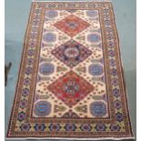 A cream ground eastern rug with three geometric medallions and multicoloured borders, 225cm long x