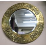 An early 20th century arts and crafts circular brass framed bevelled glass wall mirror embossed with