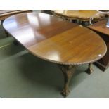 A Victorian mahogany oval wind out extending dining table and two leaves with carved edges on shaped