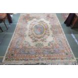 A 20th century cream ground Oriental floral rug with blue oval central medallion, floral spandrel