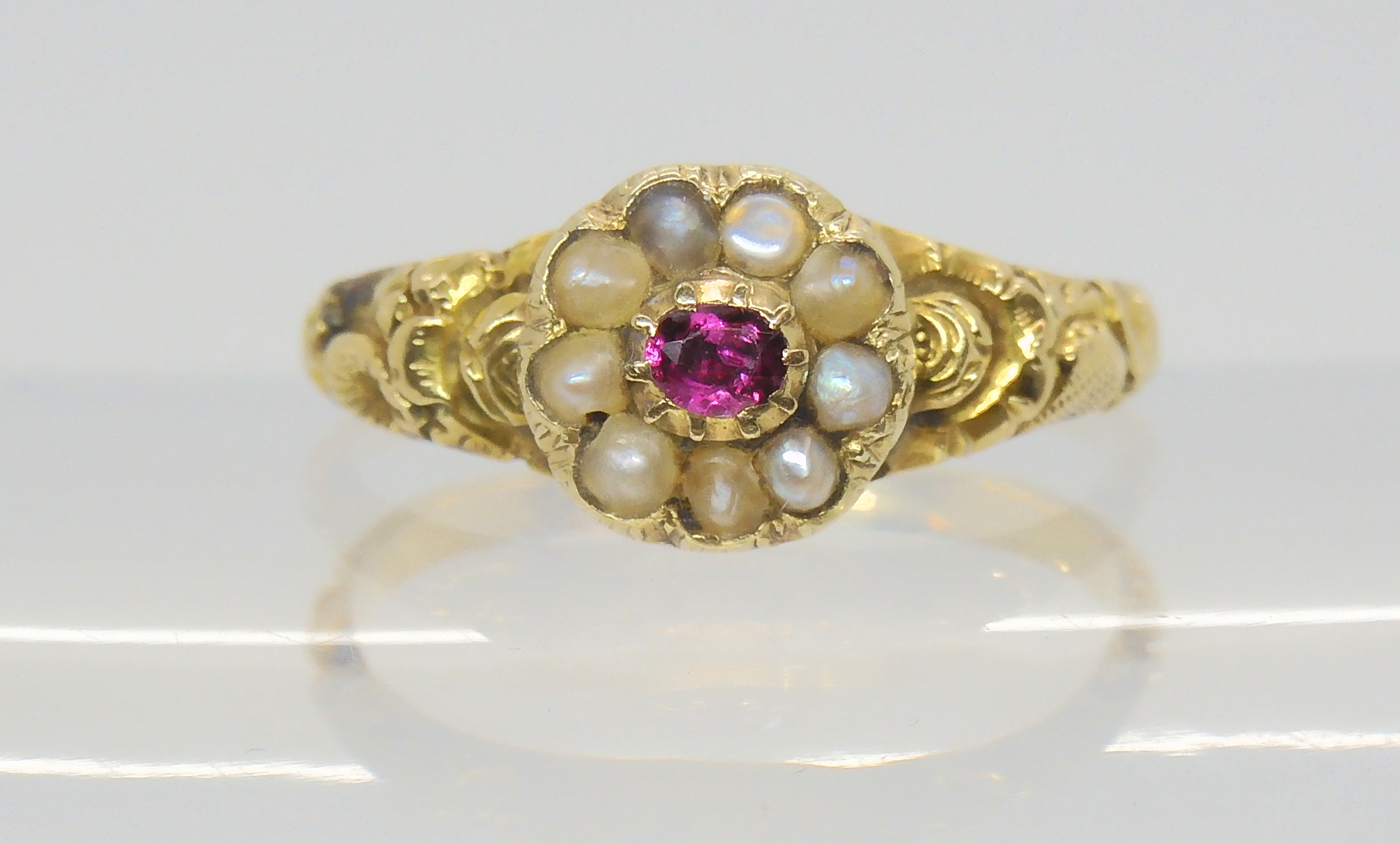 A Victorian locket ring, the hinged cover set with a ruby and pearls, with a yellow metal flower