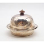 A silver butter dish and cover, the domed lid with a turned wooden finial, open to reveal a silver