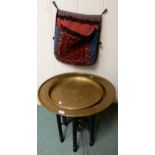 A circular brass topped Moorish folding table, circular brass tray and a woven tribal saddle bag (3)