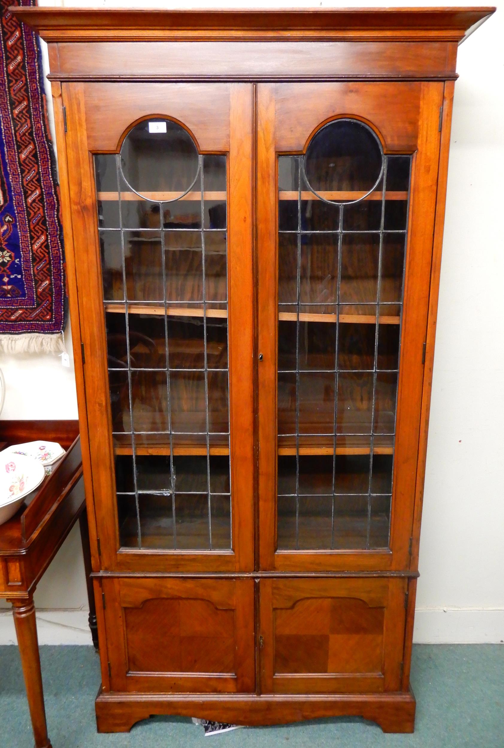 An early 20th century mahogany glazed bookcase with moulded cornice over pair of leaded glass