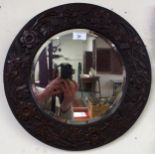 A 20th century oak arts and craft circular bevelled glass wall mirror carved with roses, thistles
