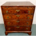 A Georgian walnut veneered chest of drawers with pull out writing slide over four graduating drawers