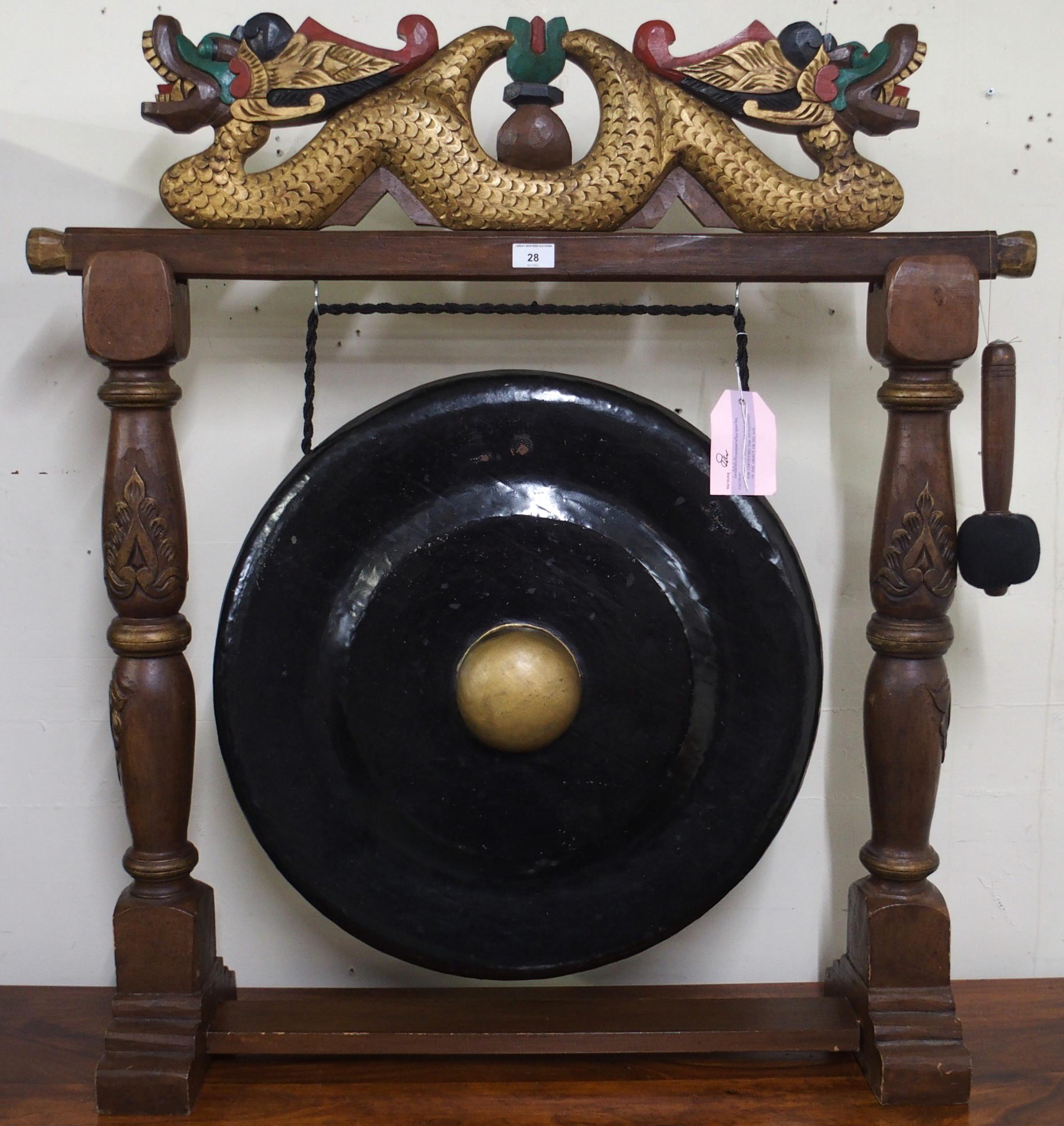 A contemporary Oriental hardwood dinner gong with carved gilt painted dragons over metal gong