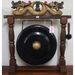 A contemporary Oriental hardwood dinner gong with carved gilt painted dragons over metal gong