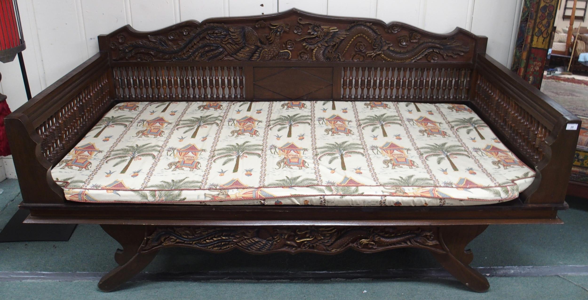 A contemporary Oriental hardwood day bed with carved back depicting phoenix and dragon over