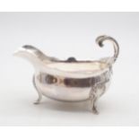 A French silver sauce boat, with a shaped rim, a flying shell and scroll handle, supported on