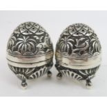 An eastern white metal salt and pepper set, of egg form, with embossed decoration of animals amongst