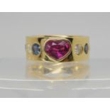 A GEM SET STATEMENT RING set with a pink heart shaped gem to the front with sapphires and diamonds