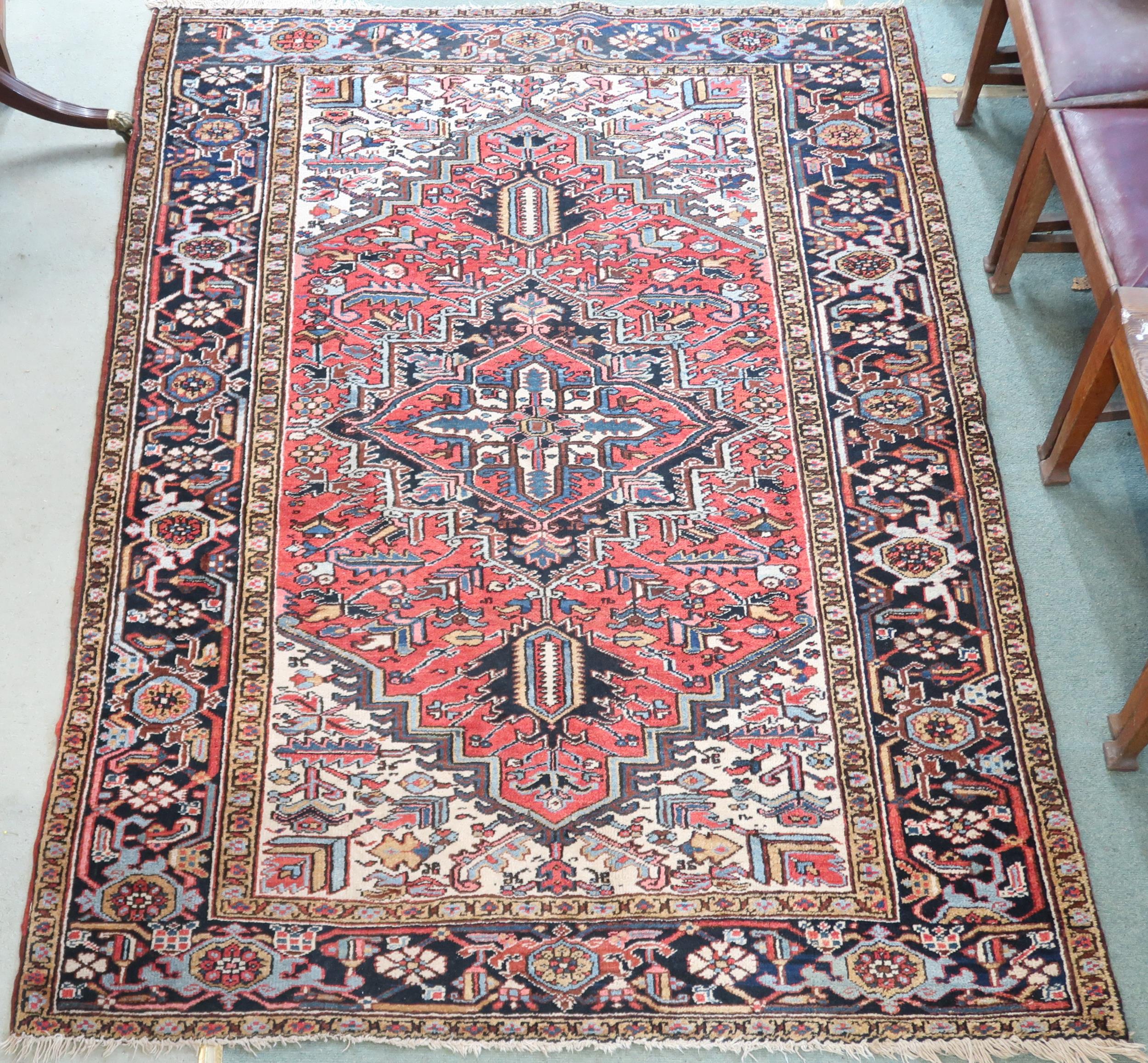 A RED GROUND KAZAK RUG with dark blue geometric central medallion, off white spandrels and geometric