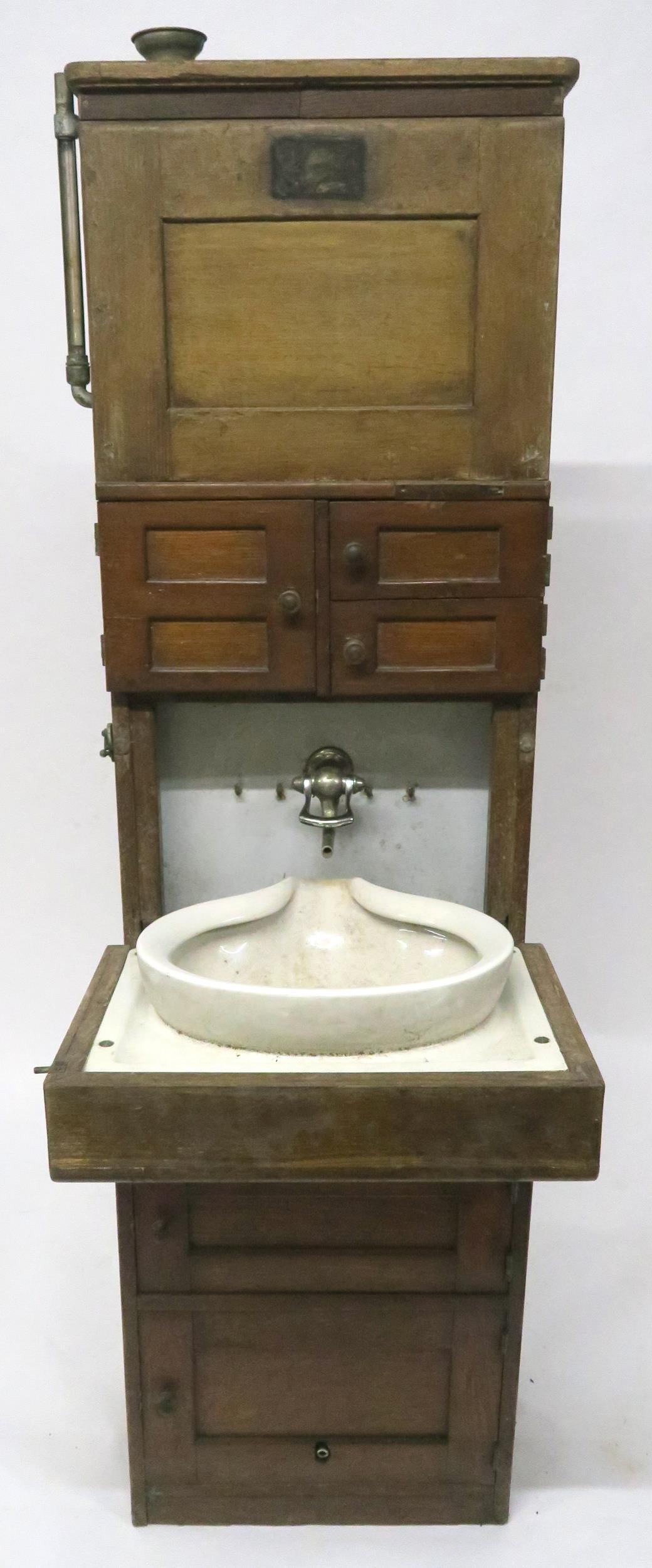 A 19/20TH CENTURY TEAK SHIPS CABIN WASH STAND with three asymmetrical cabinet doors over fall