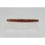 A RUBY BANGLE with a yellow metal traditional claw set mount, the rubies taper in size from