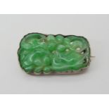 A CHINESE GREEN HARDSTONE BROOCH carved with a fruiting plant, in a white metal brooch mount.
